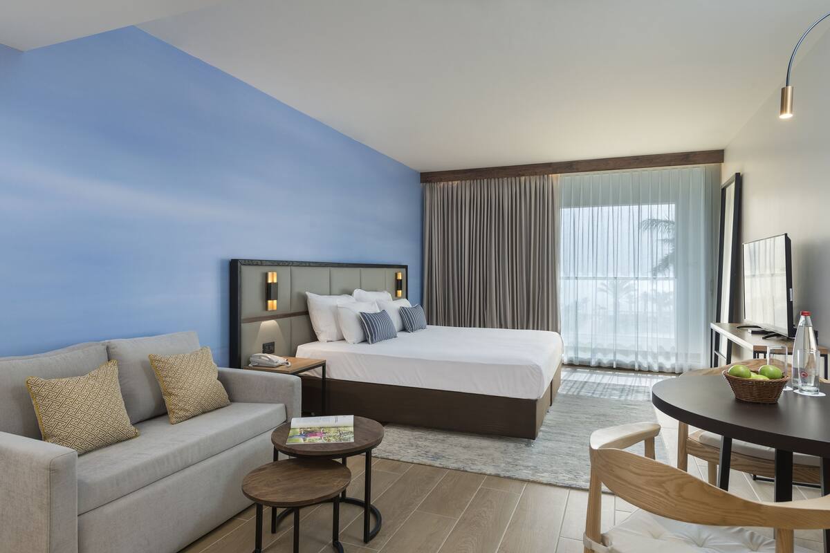 Ett modernt hotellrum med en säng, en soffa, ett litet bord och en matplats.