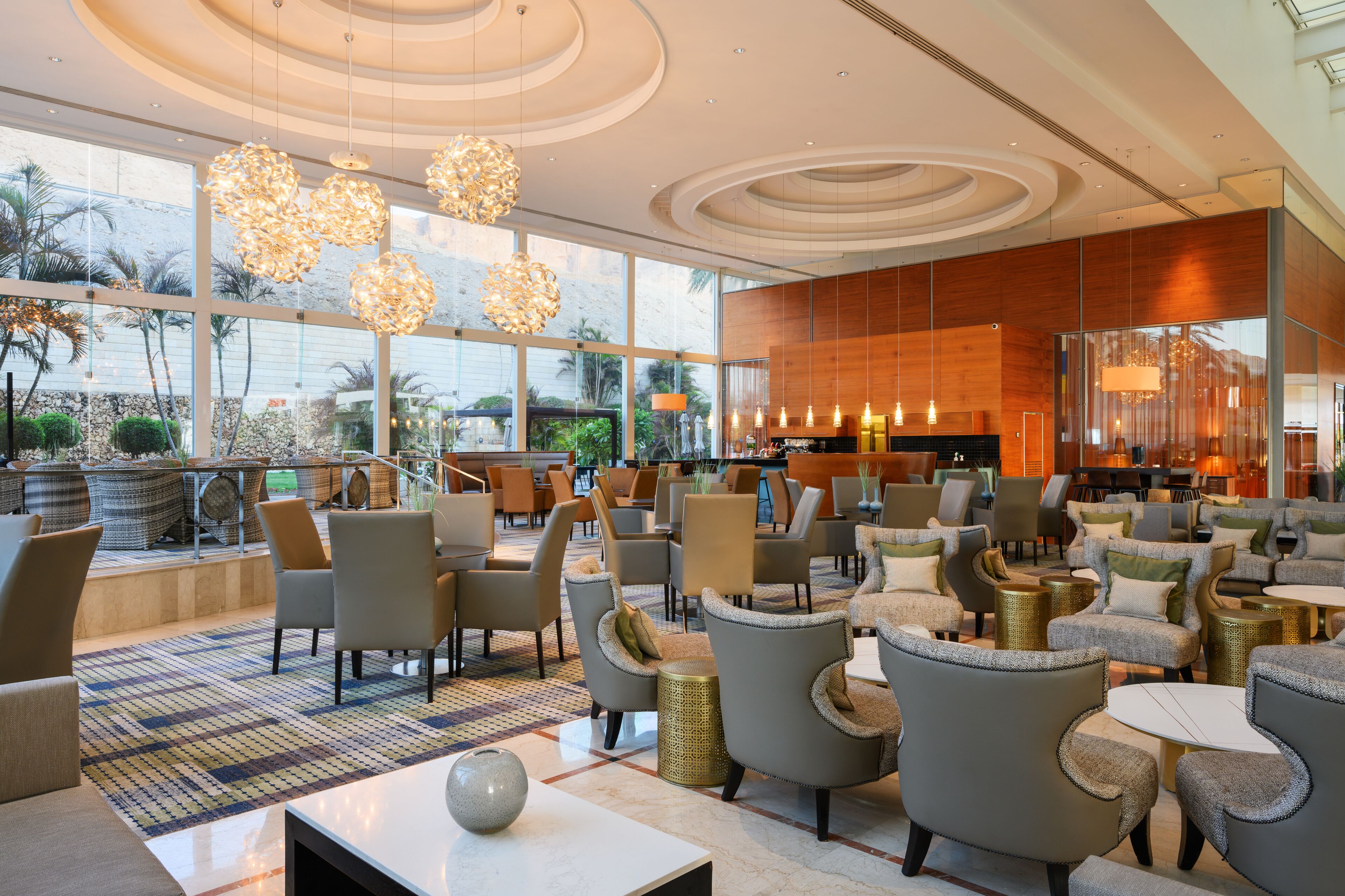 A spacious lobby with modern furniture, large windows, and decorative lighting.