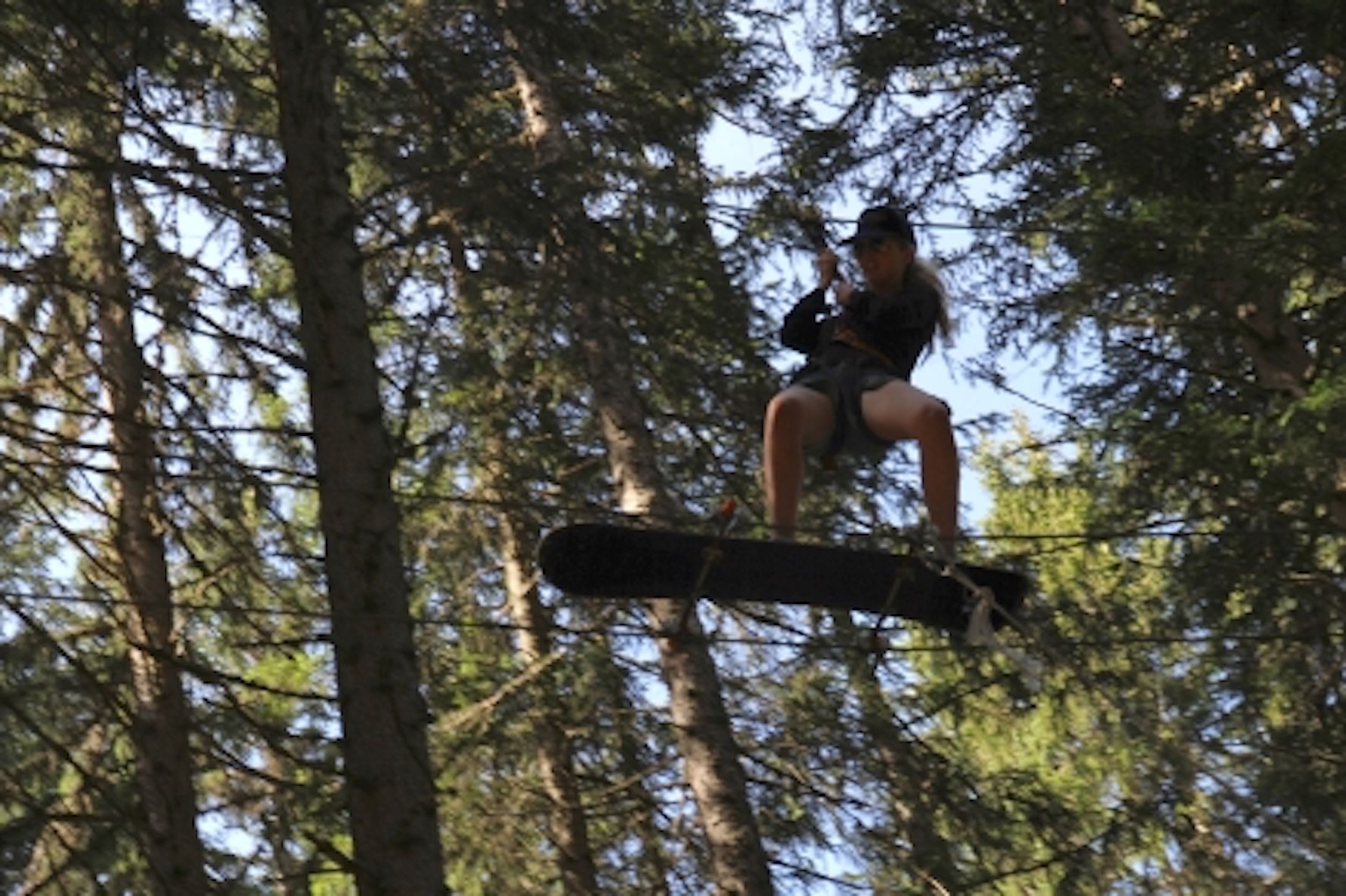 Uma pessoa em tirolesa numa floresta.