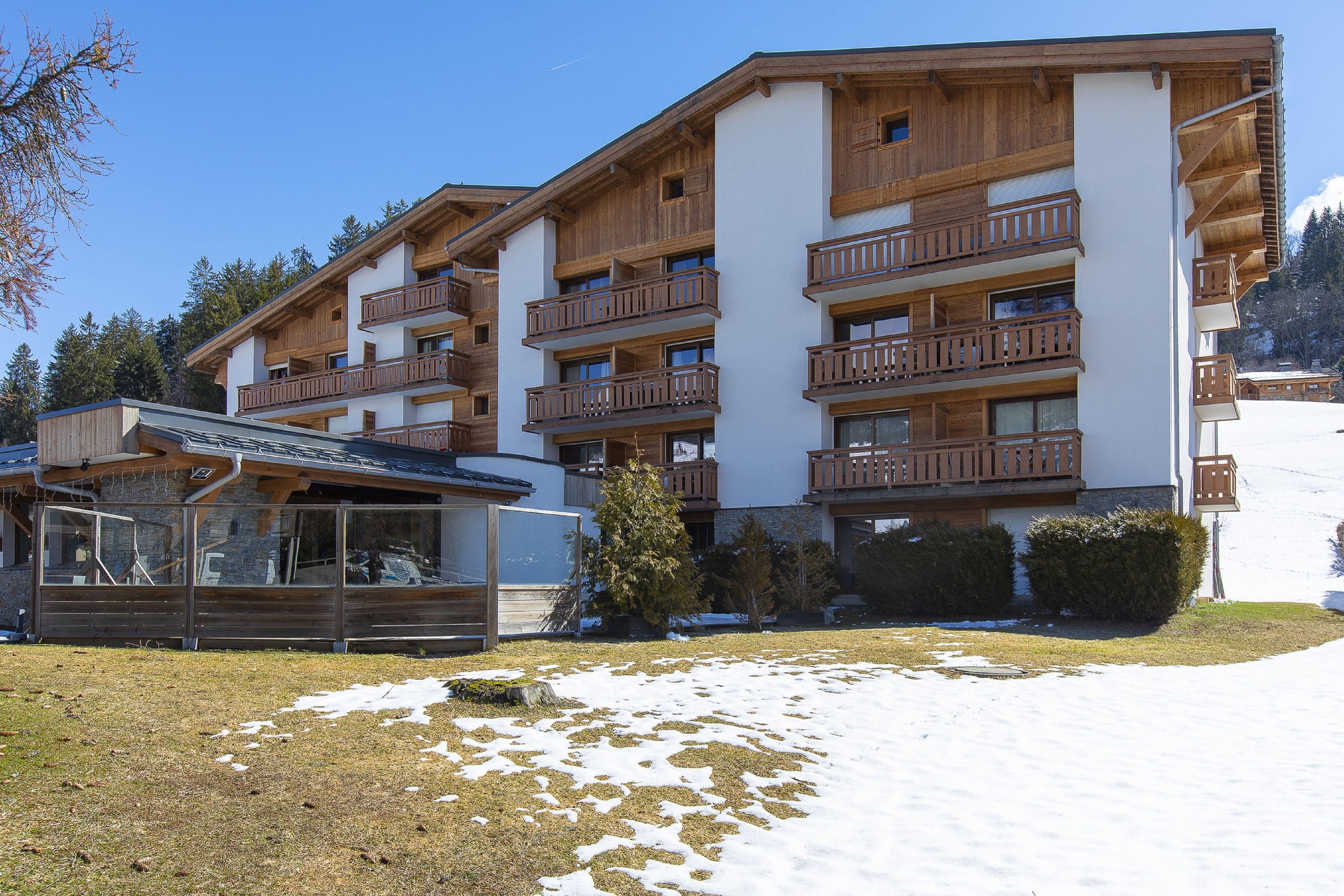 Un hôtel à plusieurs étages, doté de balcons en bois, avec une piste de ski en arrière-plan.