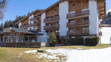 Un hôtel à plusieurs étages, doté de balcons en bois, avec une piste de ski en arrière-plan.