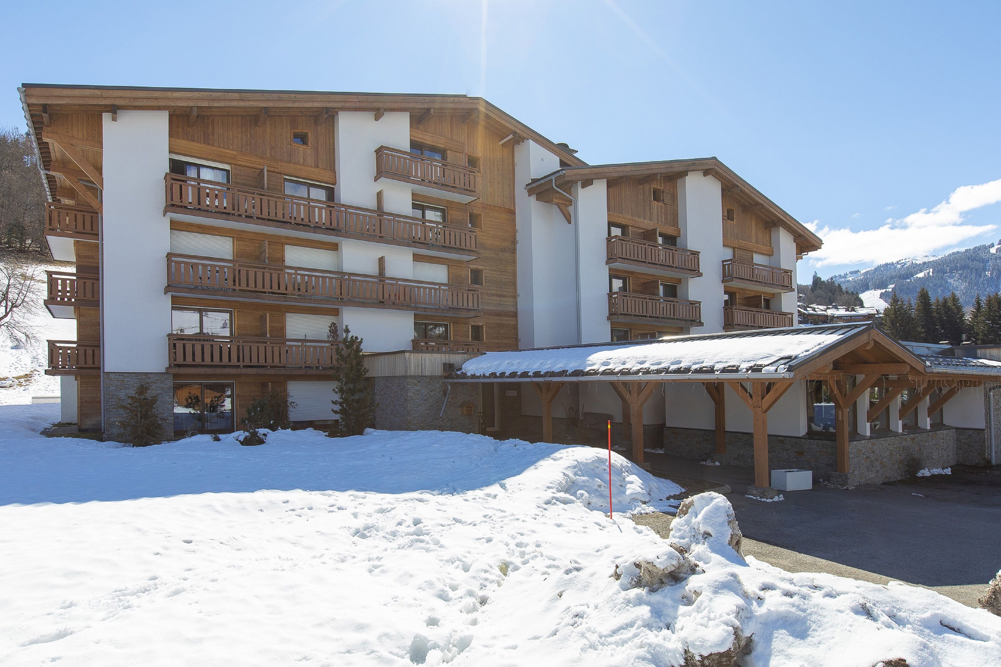 A multi-story hotel with wooden balconies and a ski slope in the background.