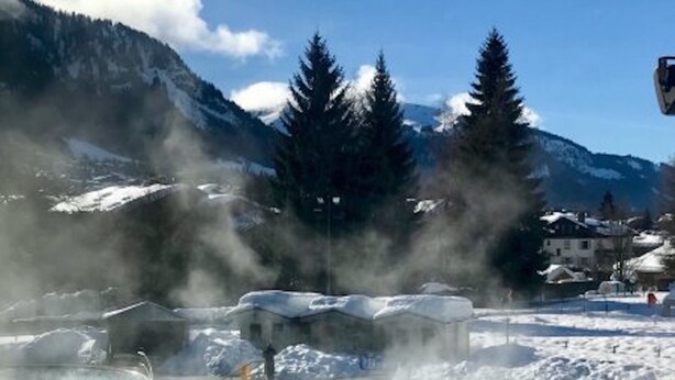 A geothermal spa surrounded by snow-covered mountains and pine trees. - Résidence Hôtel Rent (Megeve)