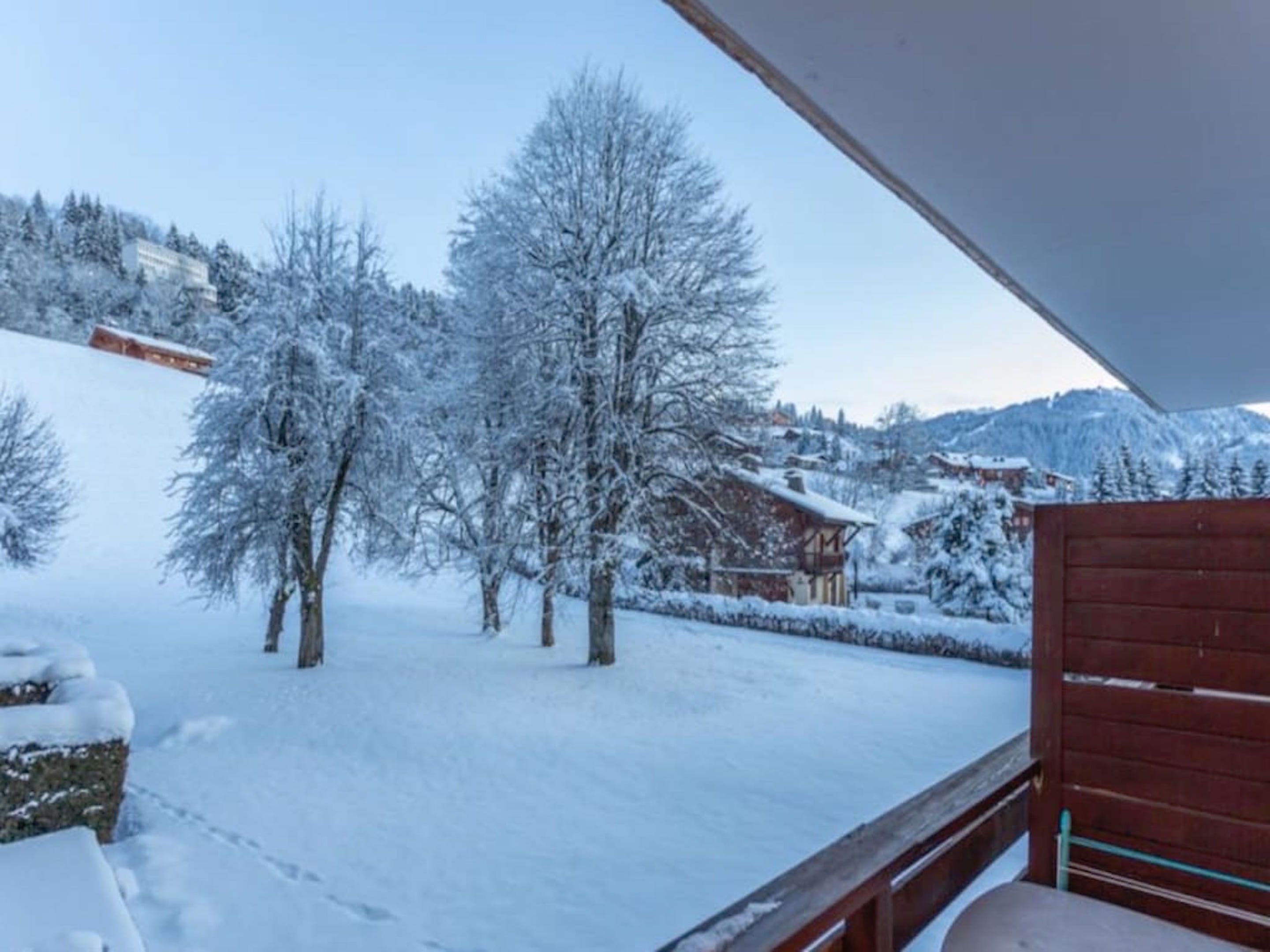 A snowy landscape with a wooden building and trees.