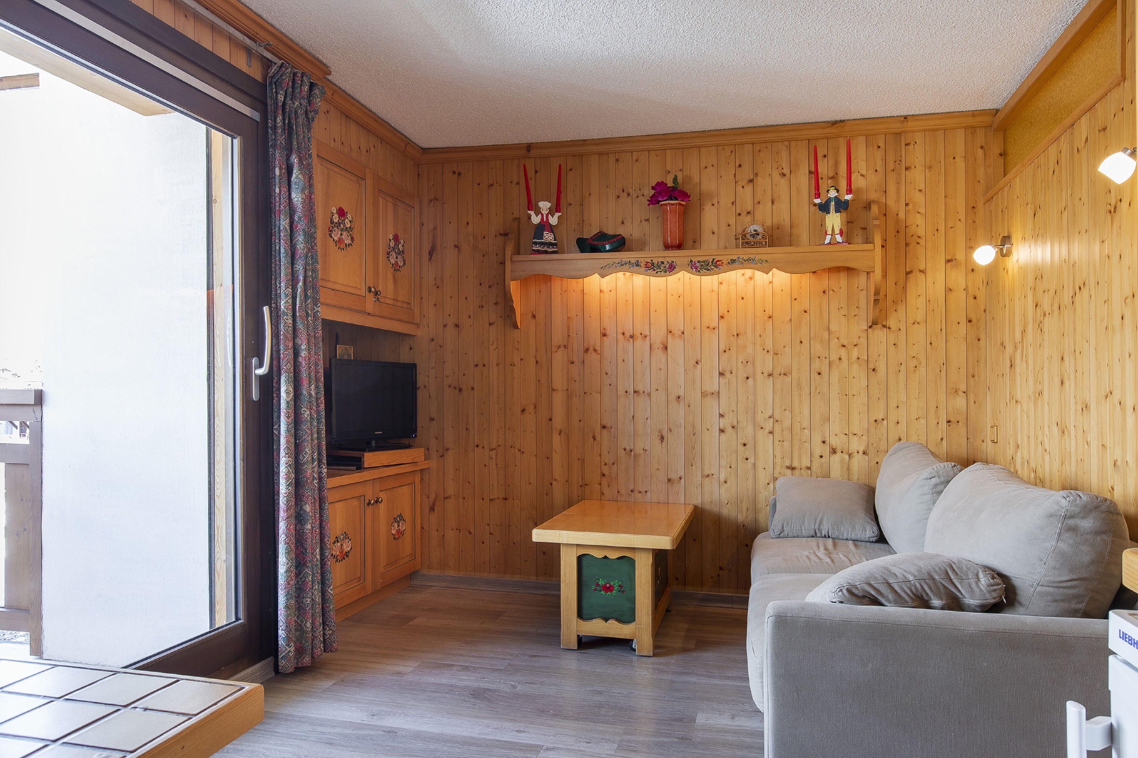 Un interior de madera con un sofá, una mesita y un televisor.