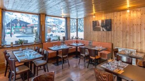 A restaurant with wooden interiors, large windows, and a view of the outside. - Résidence Hôtel Rent (Megeve)
