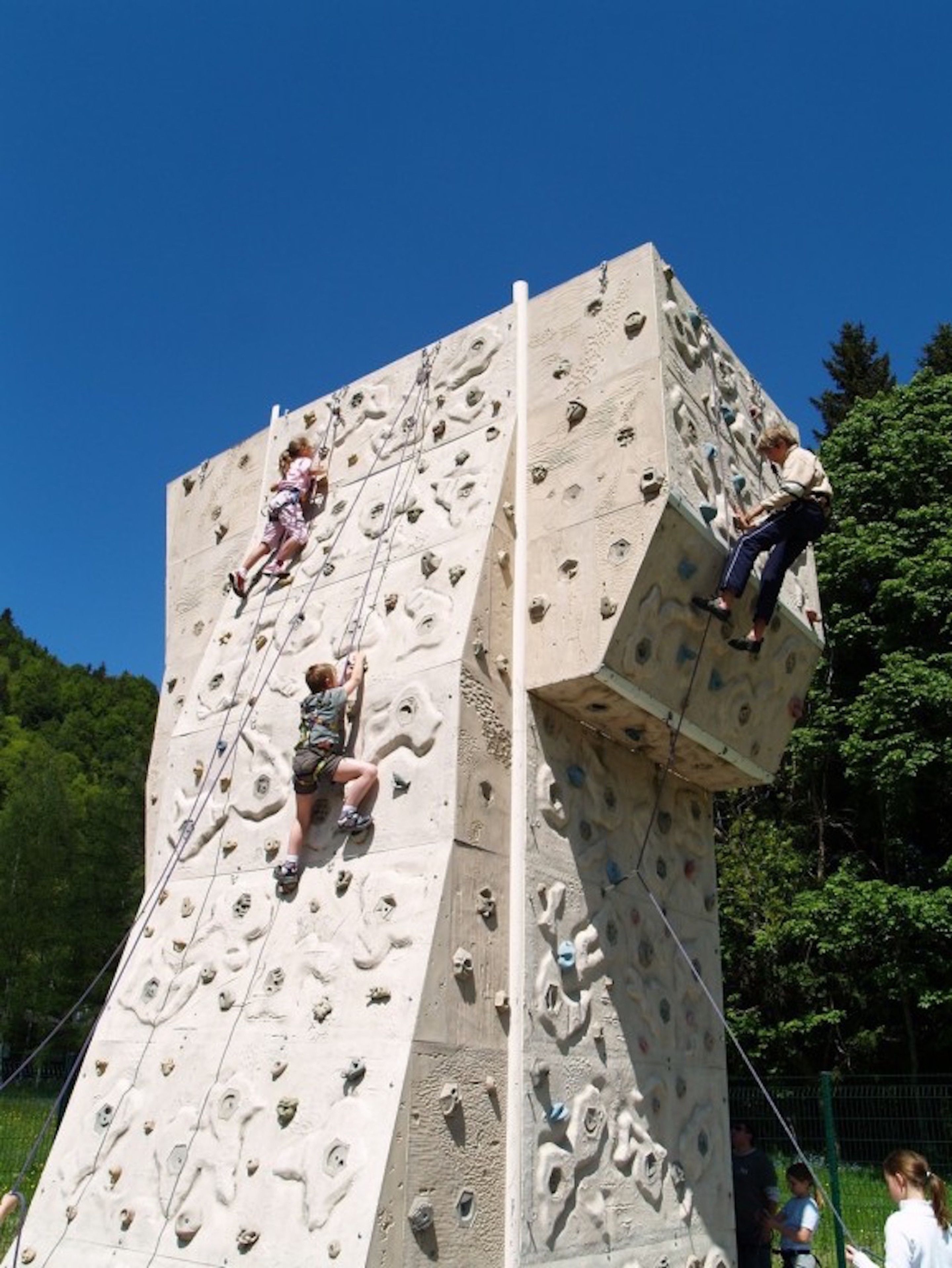 Una pared de escalada grande con múltiples rutas y una ruta vertical en el centro.
