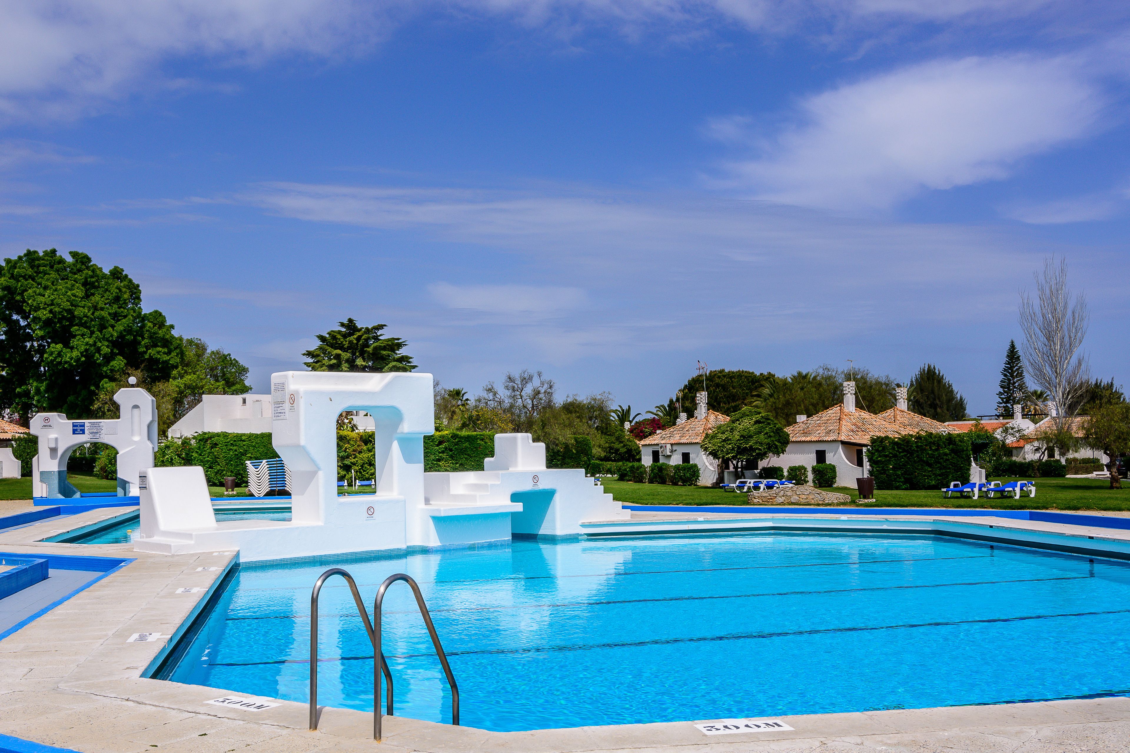 Una piscina al aire libre, sombrillas, tumbonas