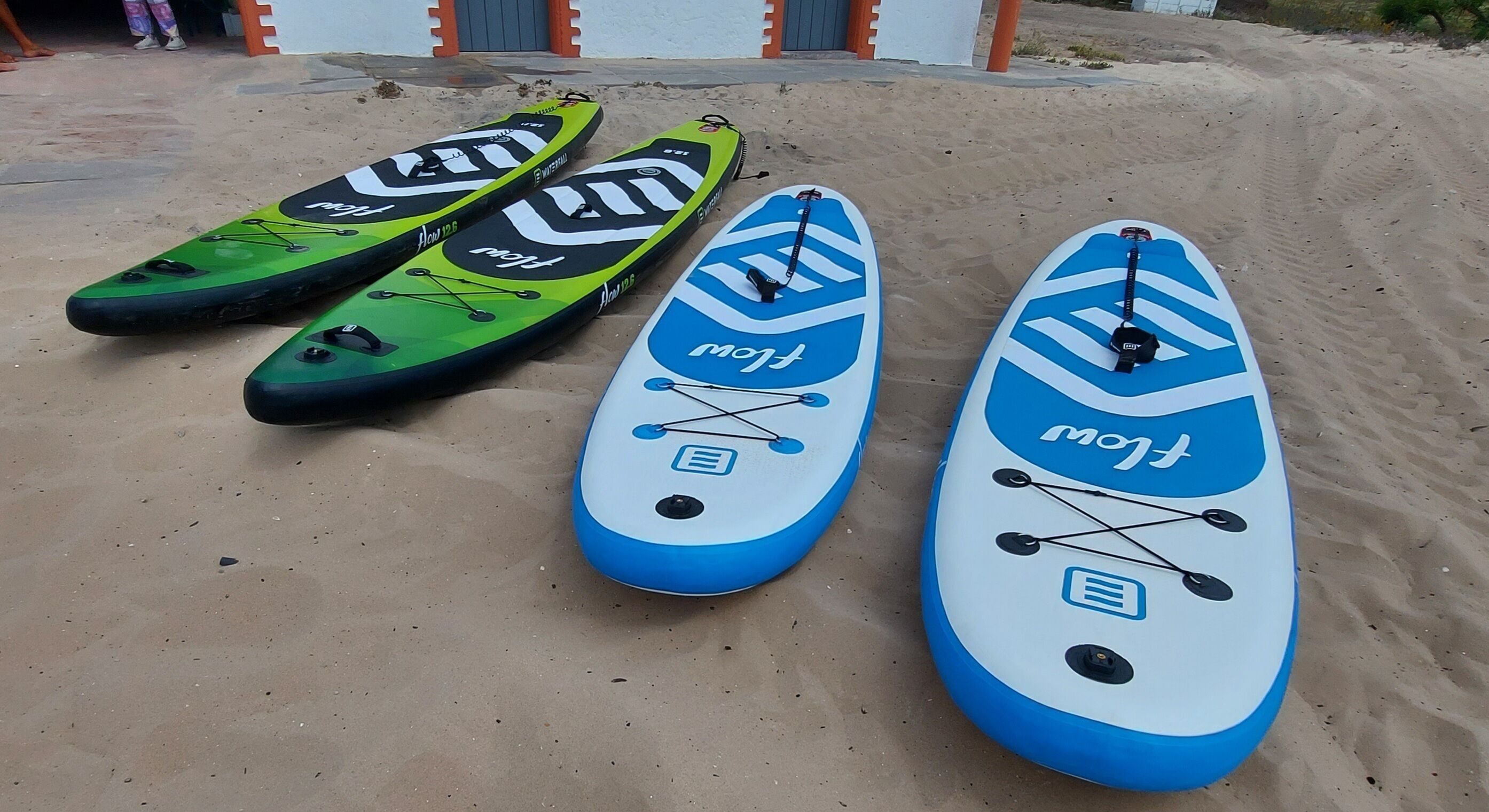 Três pranchas de stand-up paddle sobre a areia.