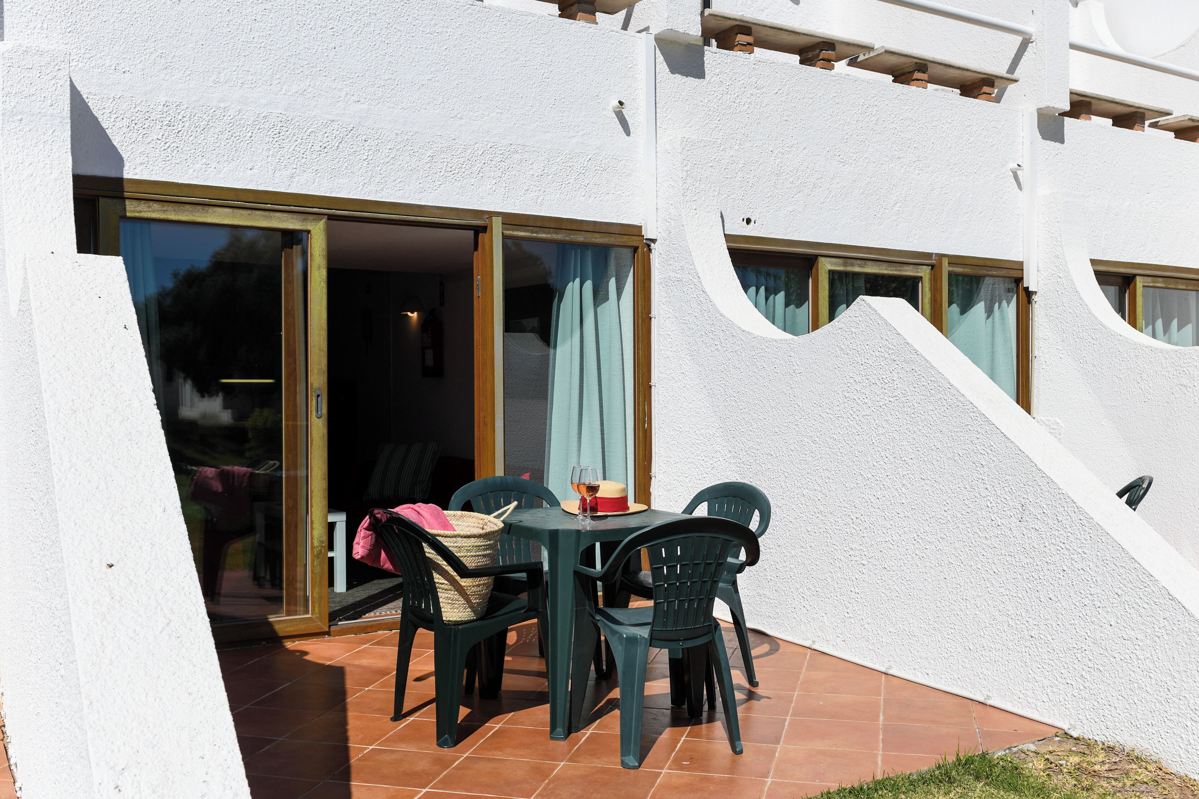 Une terrasse extérieure avec une table et des chaises, une porte-fenêtre coulissante et un petit jardin.