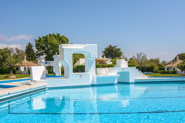 A swimming pool with a white, geometric water slide structure. - Pedras d'el Rei (Tavira)