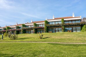 A hotel with a terraced garden, multiple balconies with red flowers, and a clear blue sky. - Pedras d'el Rei (Tavira)