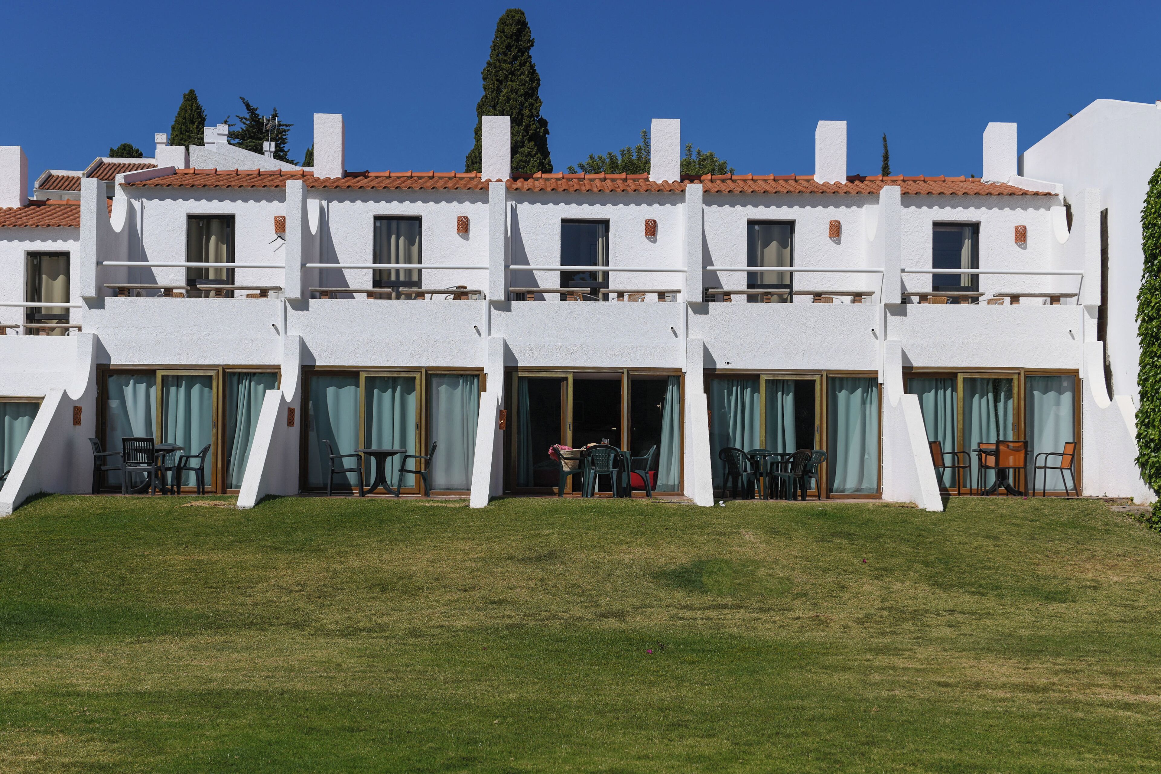 Un edificio blanco con varios balcones y puertas de vidrio correderas, probablemente un hotel o resort.