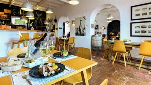 A restaurant interior with wooden tables, chairs, and hanging pendant lights. - Pedras d'el Rei (Tavira)
