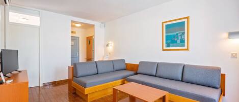 A modern living room with a sectional sofa, a wooden coffee table, and a television.
