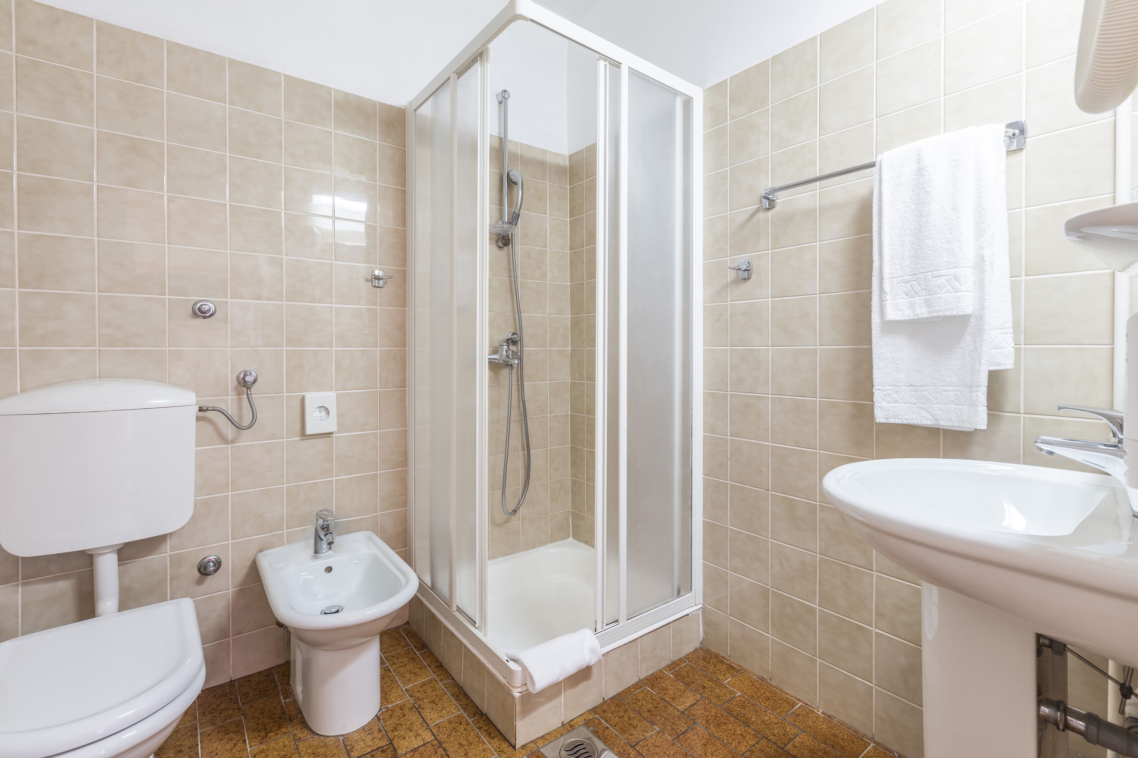 Een badkamer met toilet, bidet, douchecabine en wastafel.