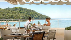 Comedor con mesas dispuestas para dos, con vistas panorámicas al litoral.