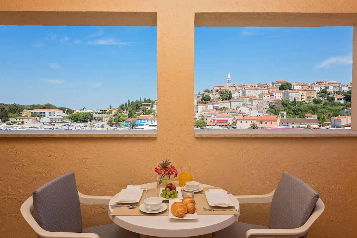 A table set with breakfast items and a view of a town with buildings and a church.