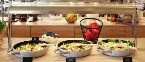 A buffet with various dishes, including salads and pasta, in a modern kitchen setting.