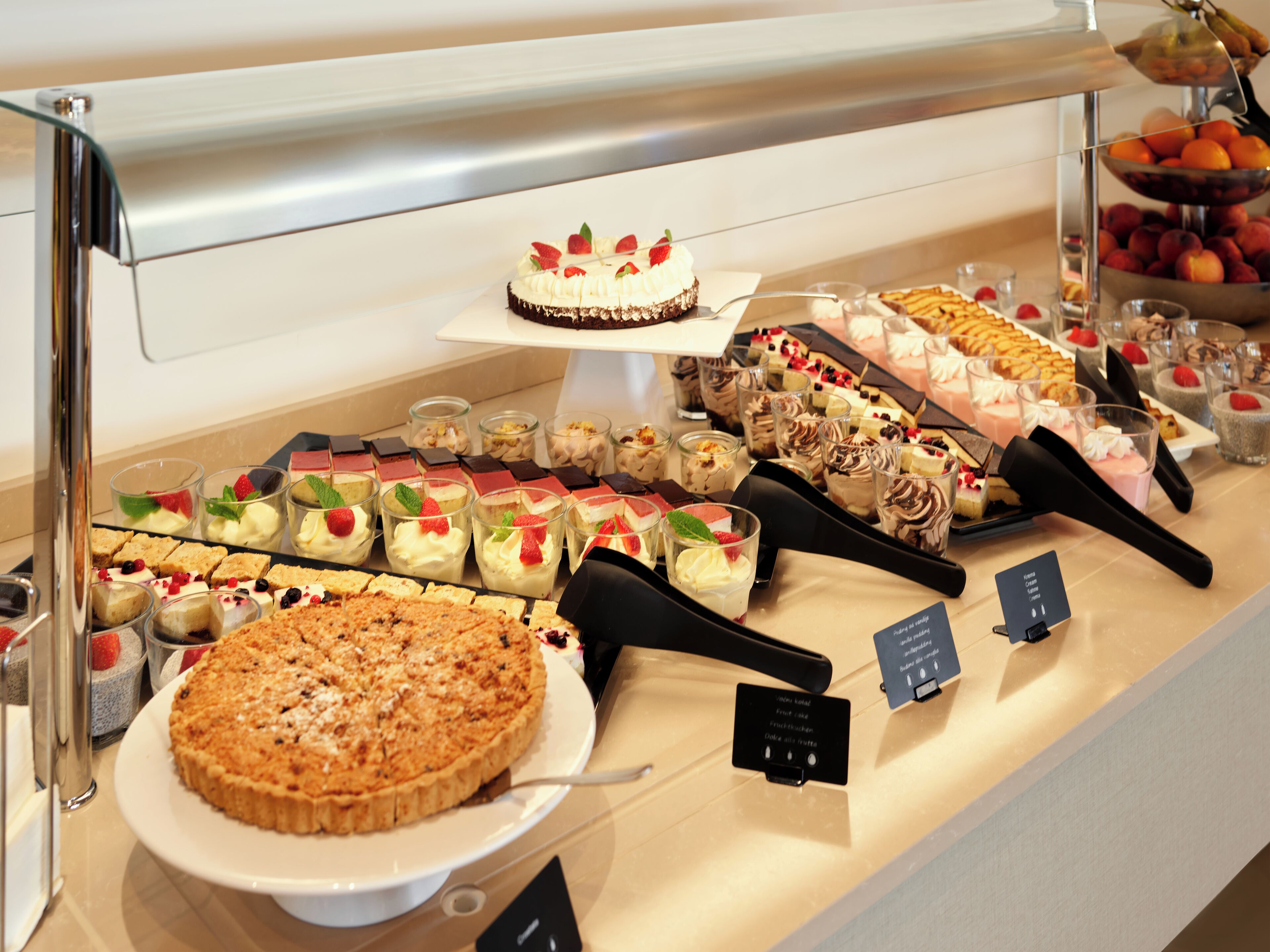 A variety of desserts displayed on a counter, including cakes, pies, and fruit tarts.