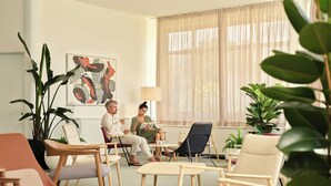 A modern living room with two people seated on sofas, a coffee table, and a potted plant. - Maistra Select Funtana All Inclusive Resort (Funtana)