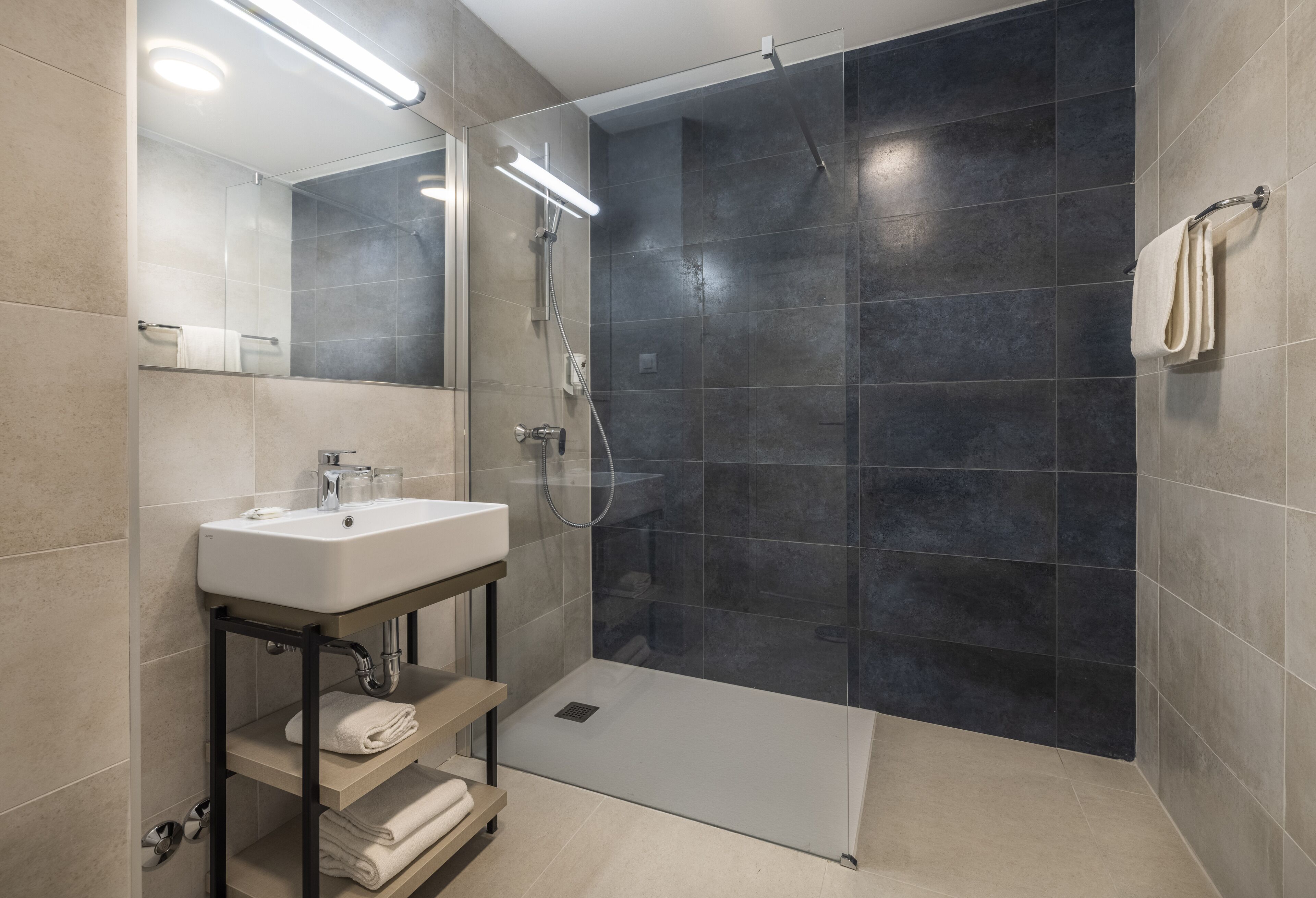 A modern bathroom with a glass-enclosed shower, a white sink, and a mirror.