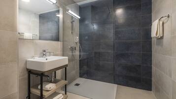 A modern bathroom with a glass-enclosed shower, a white sink, and a mirror.