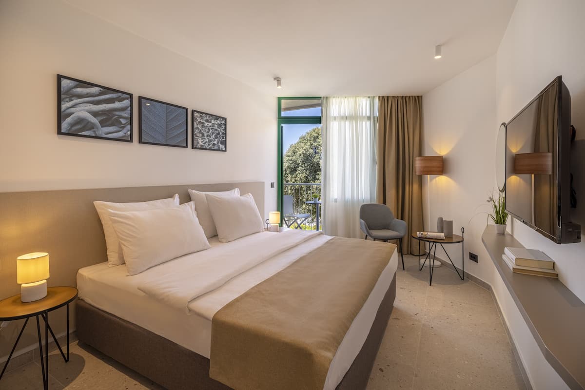 Une chambre d’hôtel avec un grand lit, un bureau, une chaise, une télévision et des œuvres d’art accrochées au mur.