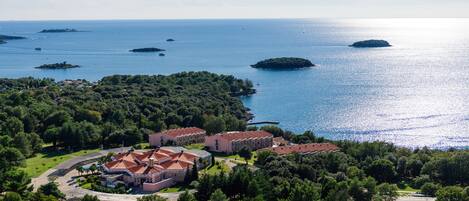 An aerial view of a coastal property with multiple buildings, a large body of water, and several small islands.