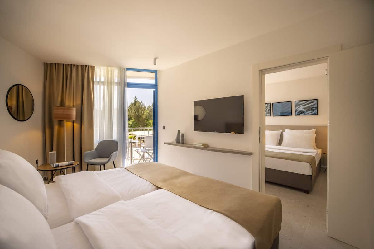 Une chambre d’hôtel avec deux lits, une télévision, un bureau avec une lampe et une vue sur l’extérieur.
