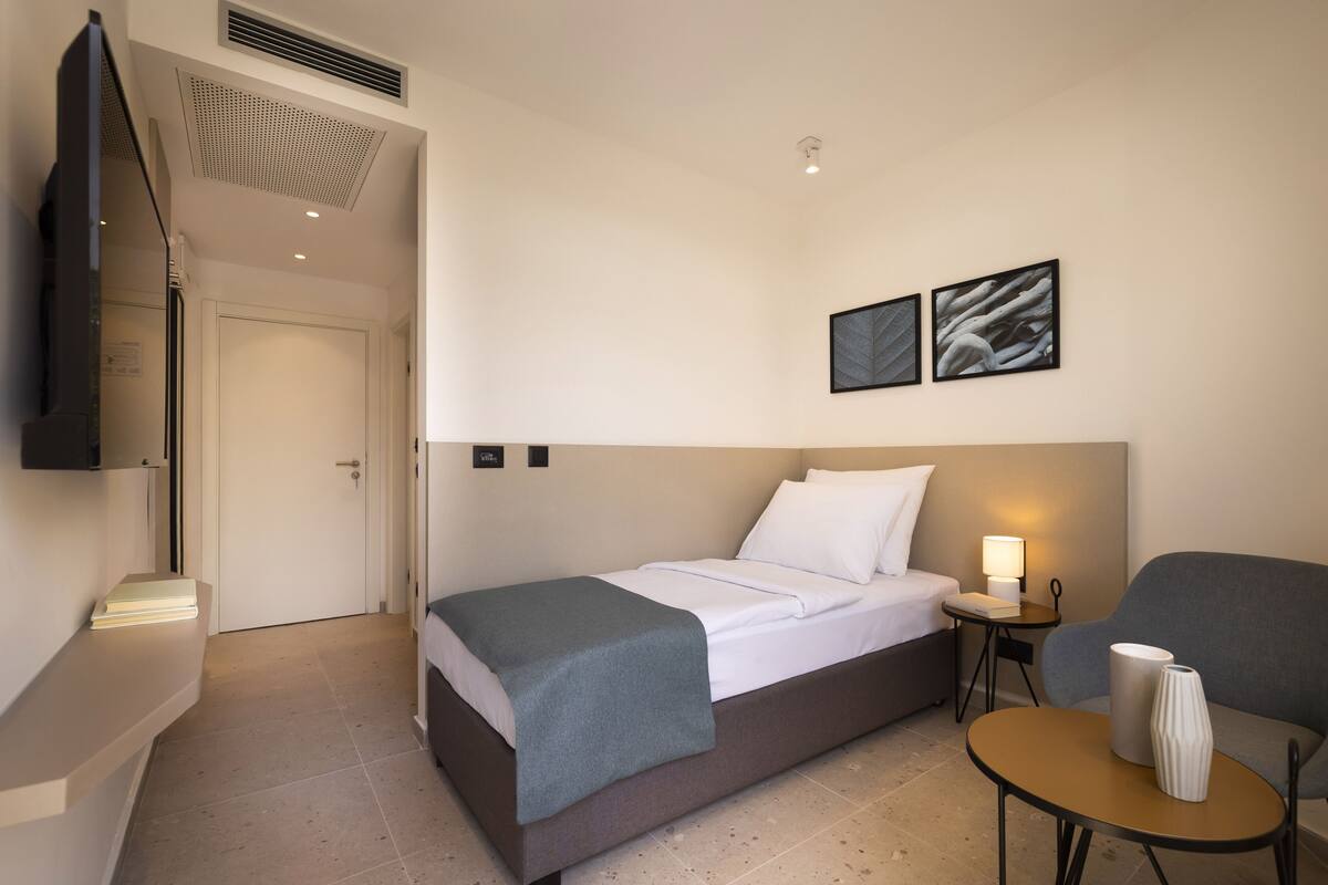 Une chambre d’hôtel avec un lit, des tables de chevet, une télévision et des œuvres d’art accrochées au mur.