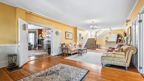 Un vaste salon doté de planchers en bois franc, d’un grand tapis, d’un canapé et d’un escalier menant à l’étage supérieur.
