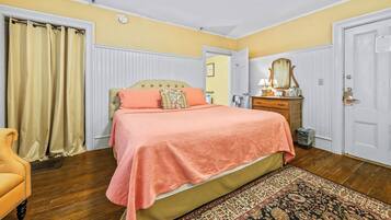 A bedroom with a bed, a dresser, a mirror, a chair, and a door.
