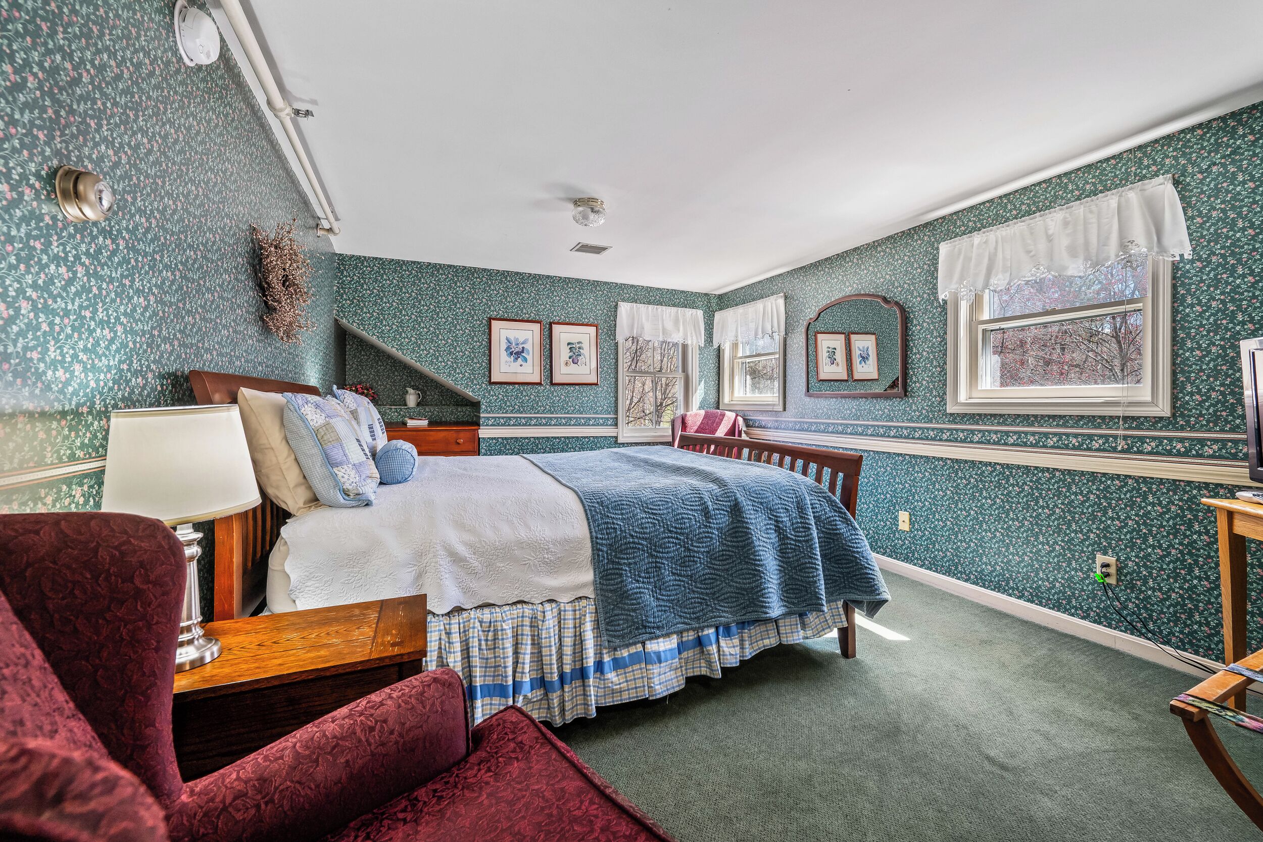 A bedroom with a bed, a chair, a lamp, and a window with a view.