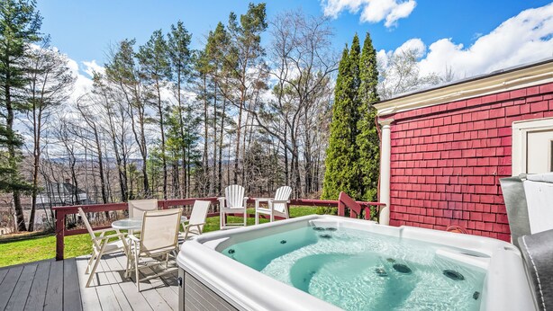 Un bain à remous sur une terrasse, avec des chaises, et un bâtiment rouge en arrière-plan.
