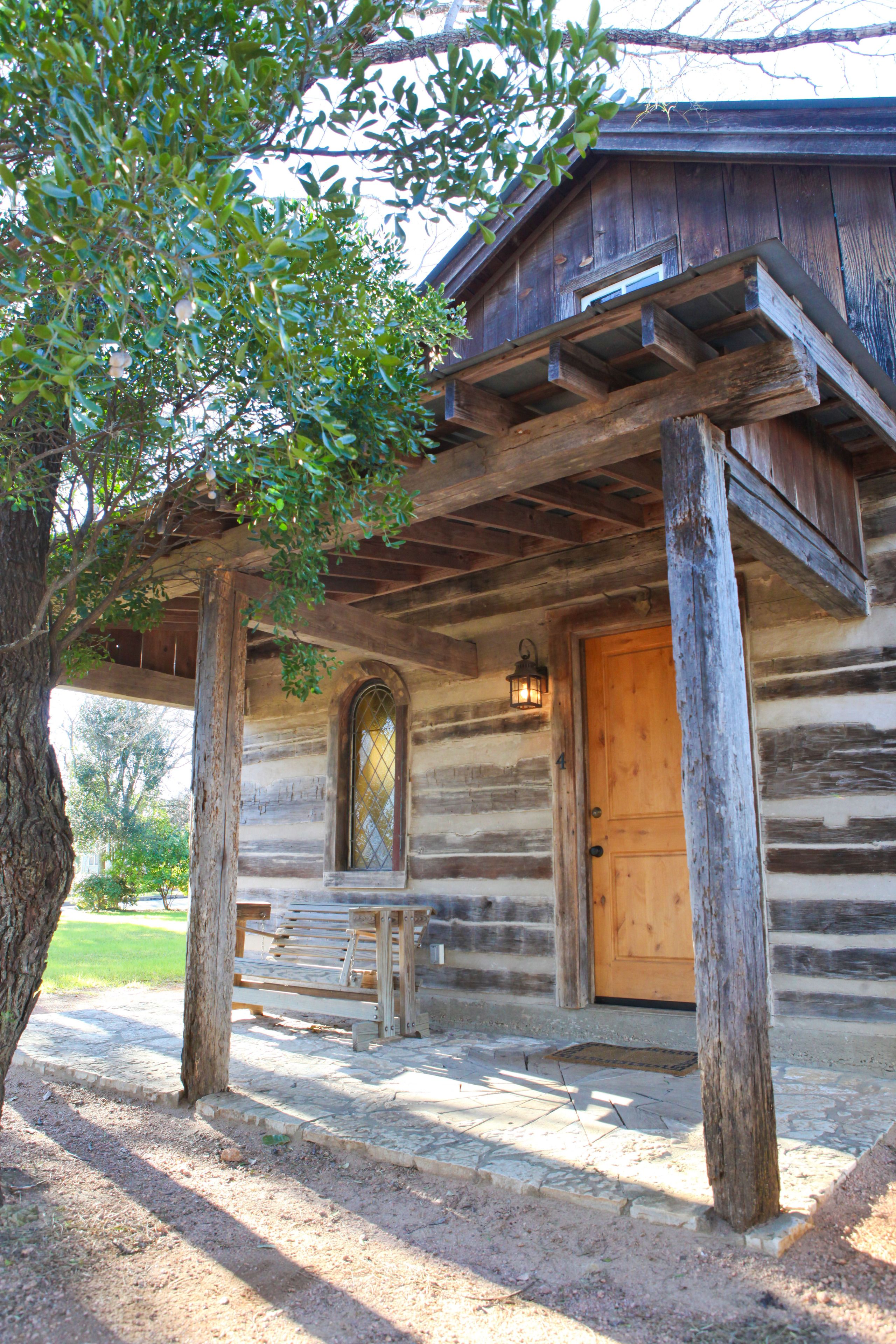 Un rustico chalet in legno con veranda, una panca e una porta con finestra.