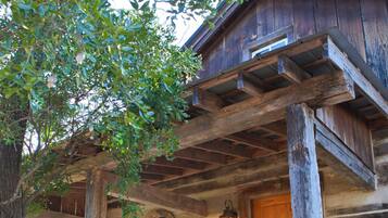 A rustic log cabin with a wooden porch, a bench, and a door with a window.