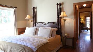 A neatly made bed with a wooden headboard, two bedside lamps, and a small table with a vase.