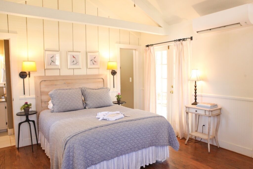 A neatly arranged bedroom with a large bed, two bedside tables with lamps, and a small side table.