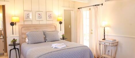 A neatly arranged bedroom with a large bed, two bedside tables with lamps, and a small side table.