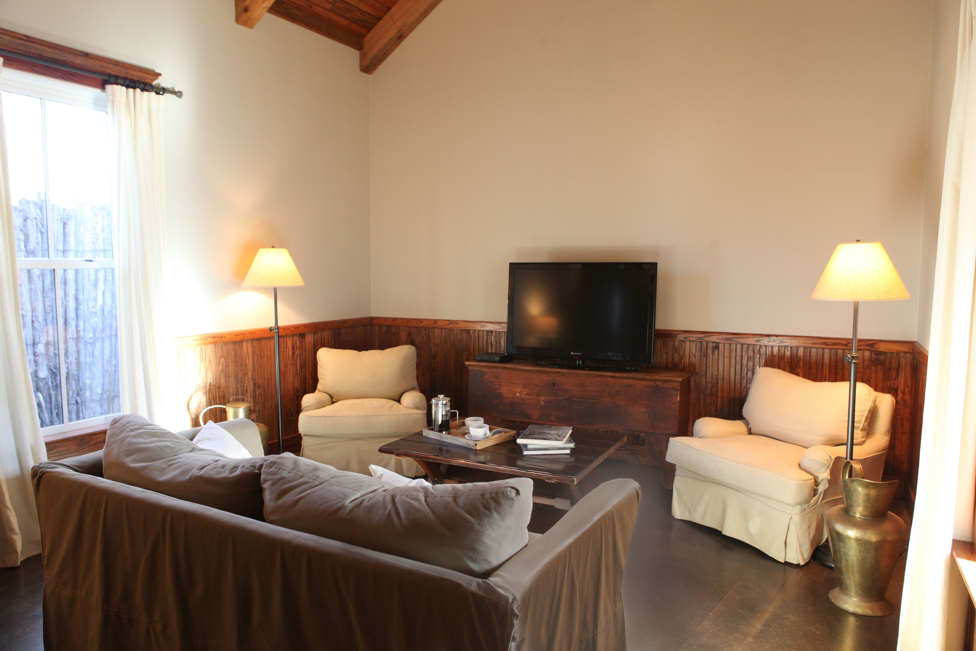 A living room with a sofa, two armchairs, a coffee table, a television, and lamps.