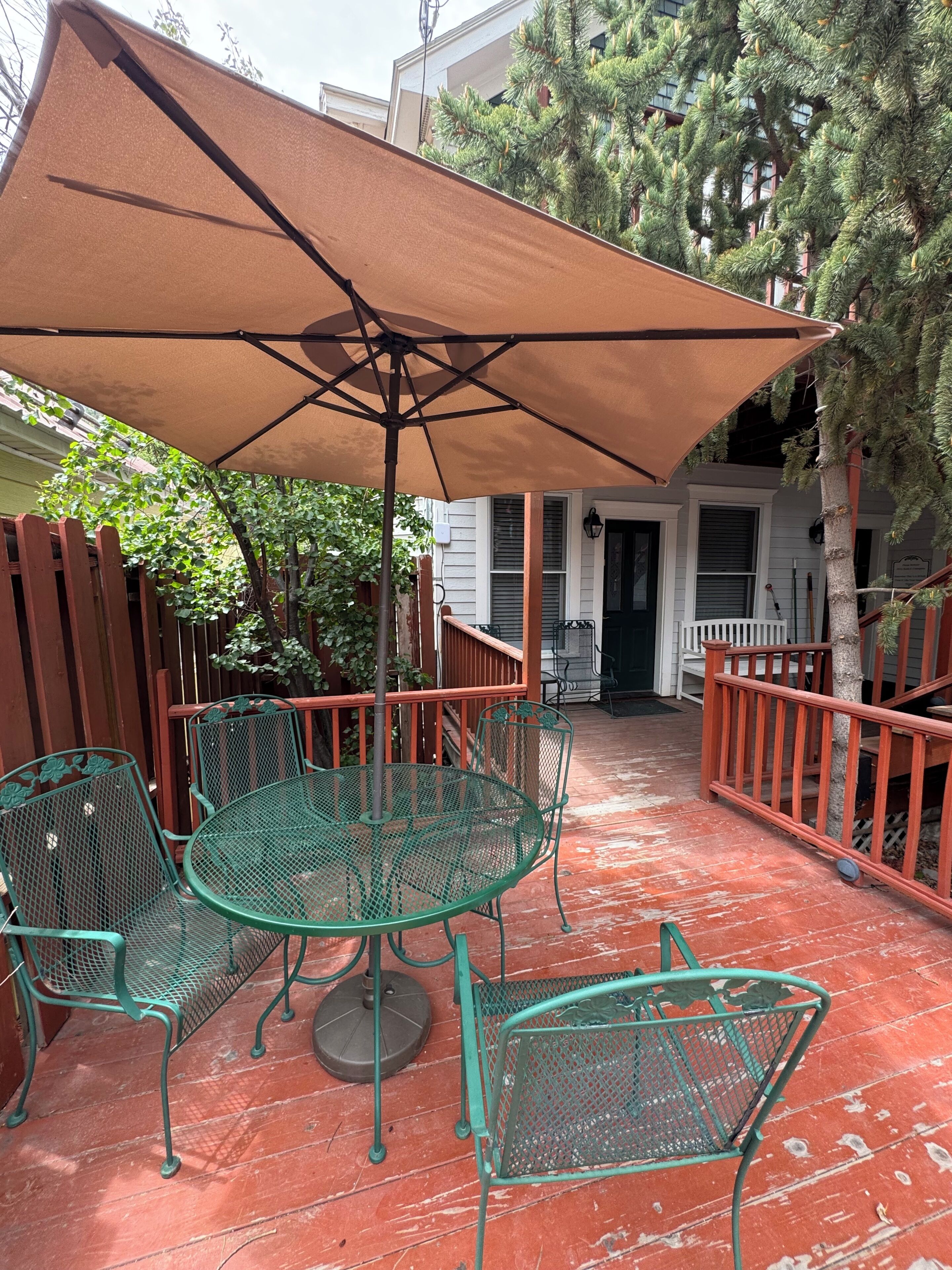 A patio with a table and chairs, a large umbrella, and a wooden fence.