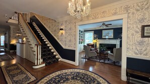 A staircase with a black and white design, a chandelier, and a fireplace. - The Clipper Inn Bed & Breakfast (Ouray)