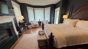 A bedroom with a large bed, a fireplace, a desk, and a chair. - The Clipper Inn Bed & Breakfast (Ouray)