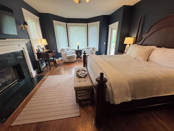 A bedroom with a large bed, a fireplace, a desk, and a chair. - The Clipper Inn Bed & Breakfast (Ouray)