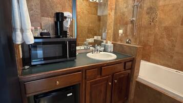Un baño con tocador de madera, lavamanos, espejo, ducha y lámpara en el techo.