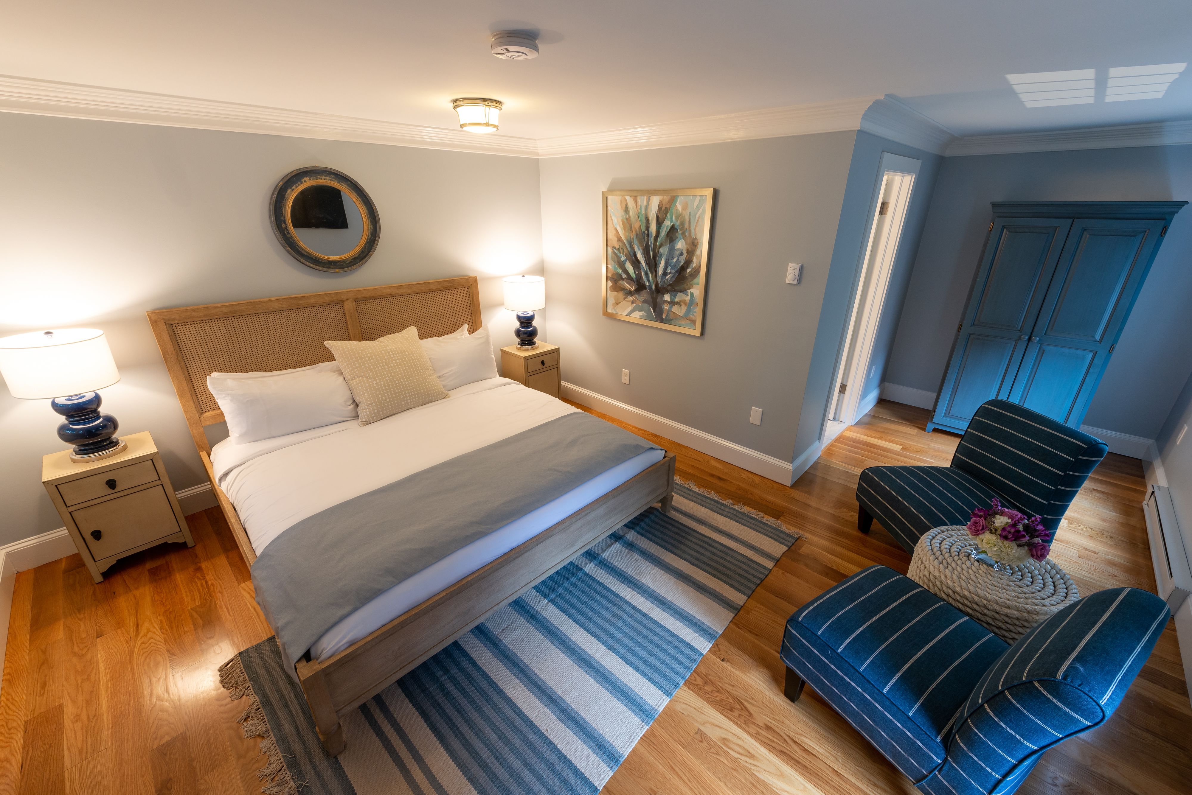 Ein Schlafzimmer mit einem Bett, Nachttischen, einem Sessel, einem Teppich und einem Bild an der Wand.