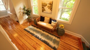 A wooden-floored hallway with a rattan bench, a potted plant, and a painting on the wall. - Town & Tide Inn (Newport)