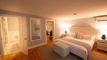 A bedroom with a large bed, bedside tables, a mirror, and a door leading to another room.