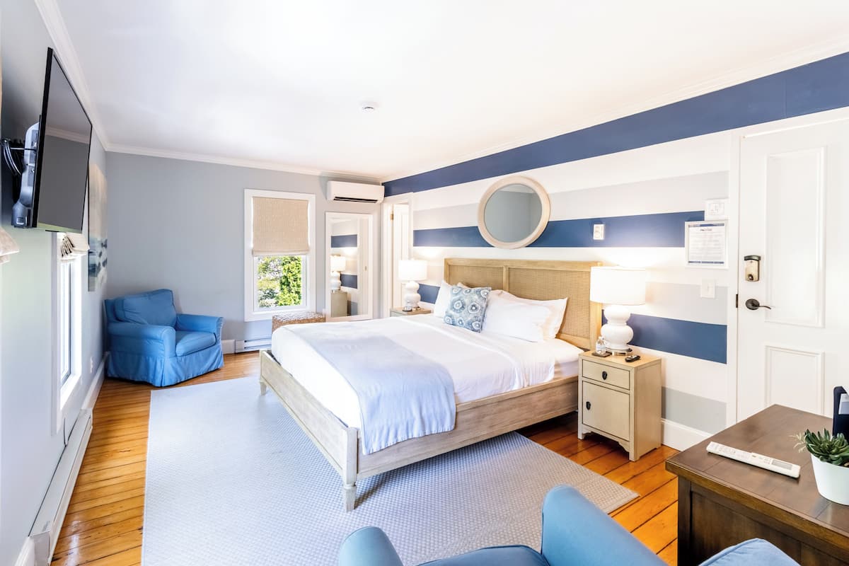 A modern bedroom with a bed, bedside tables, a TV, and a blue armchair.